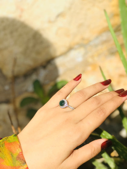 An alluring dark green emerald stone surrounded by small shiny diamonds (925 Sterling Silver)